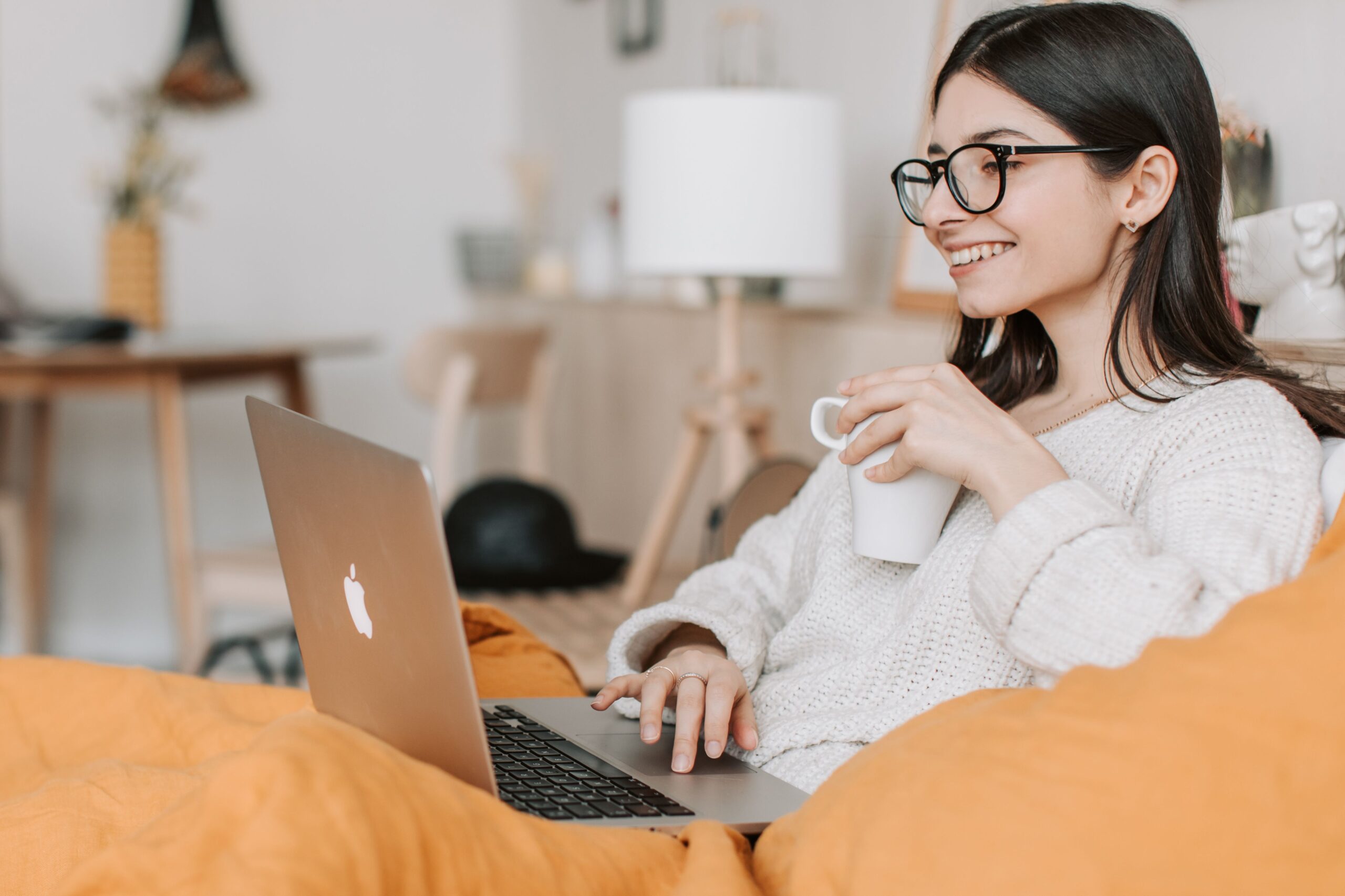 A person smiling while joining an online therapy session on a laptop at home