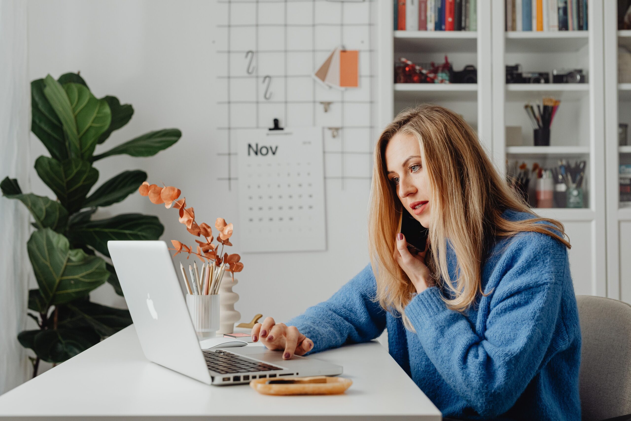 A woman on a phone and laptop during an online therapy session