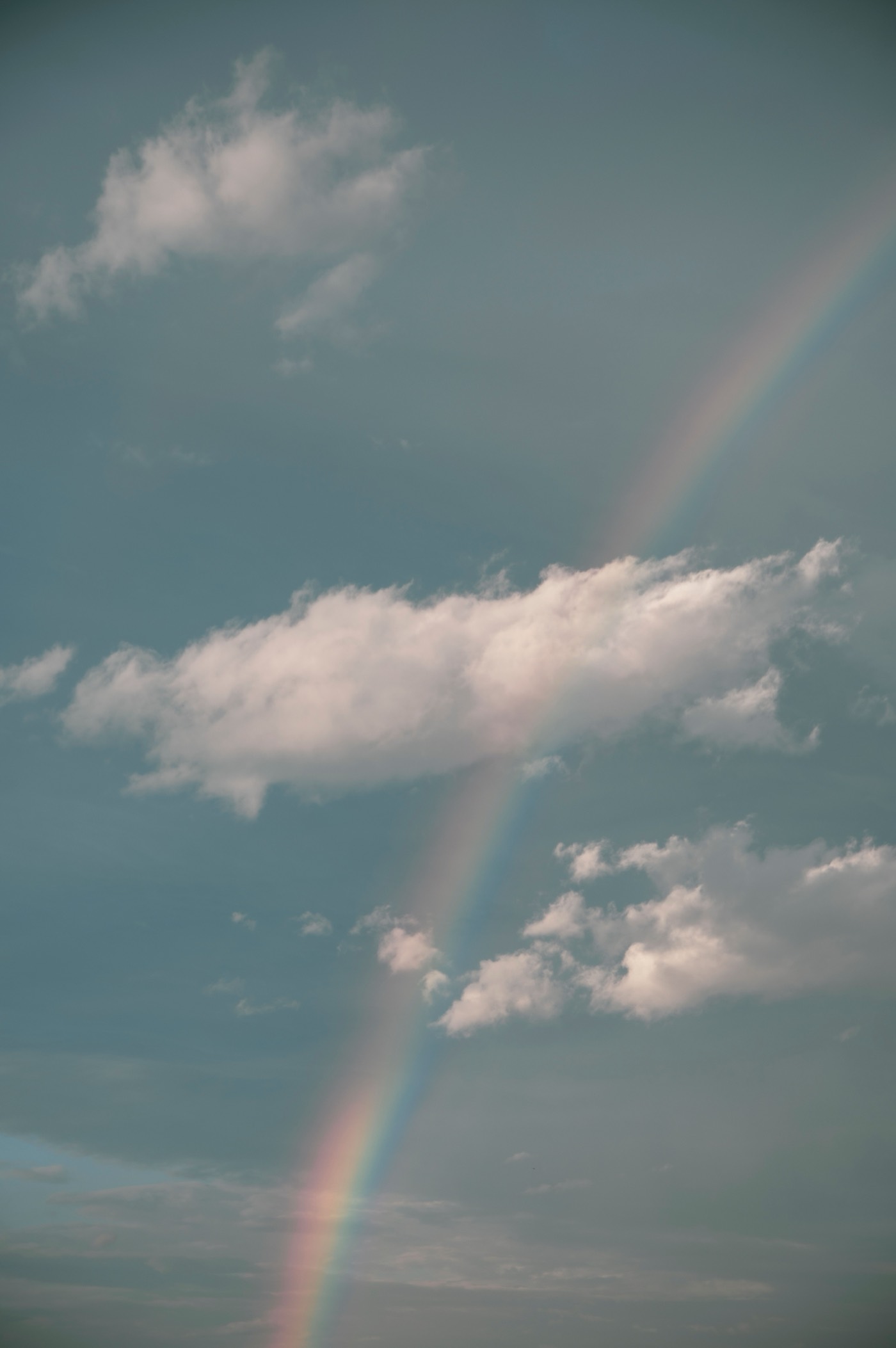 A faint rainbow across an open, clearing sky over New York.